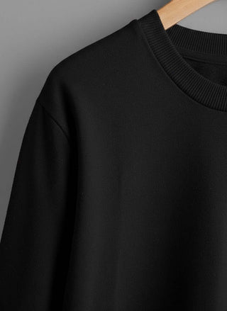 COTTON FRENCH TERRY DROP SHOULDER T-SHIRTS in black hanging on a wooden hanger, showcasing the neckline and fabric.