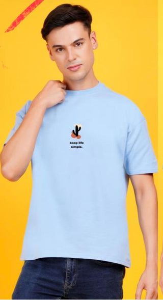 TERRY DROP SHOULDER T-SHIRTS PRINTED model wearing a light blue t-shirt with printed design on a vibrant yellow background.